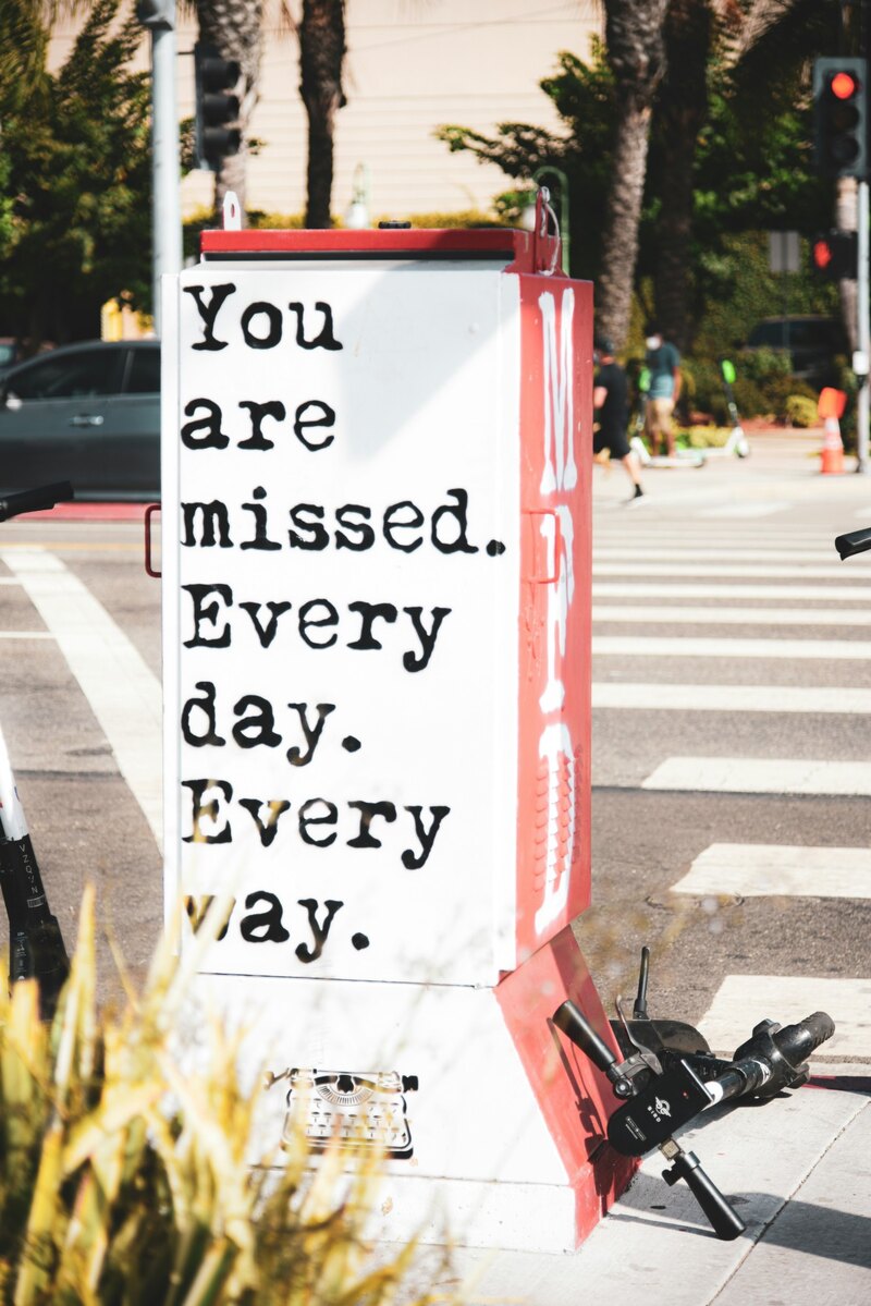 A stenciled street box that says You are missed, Before