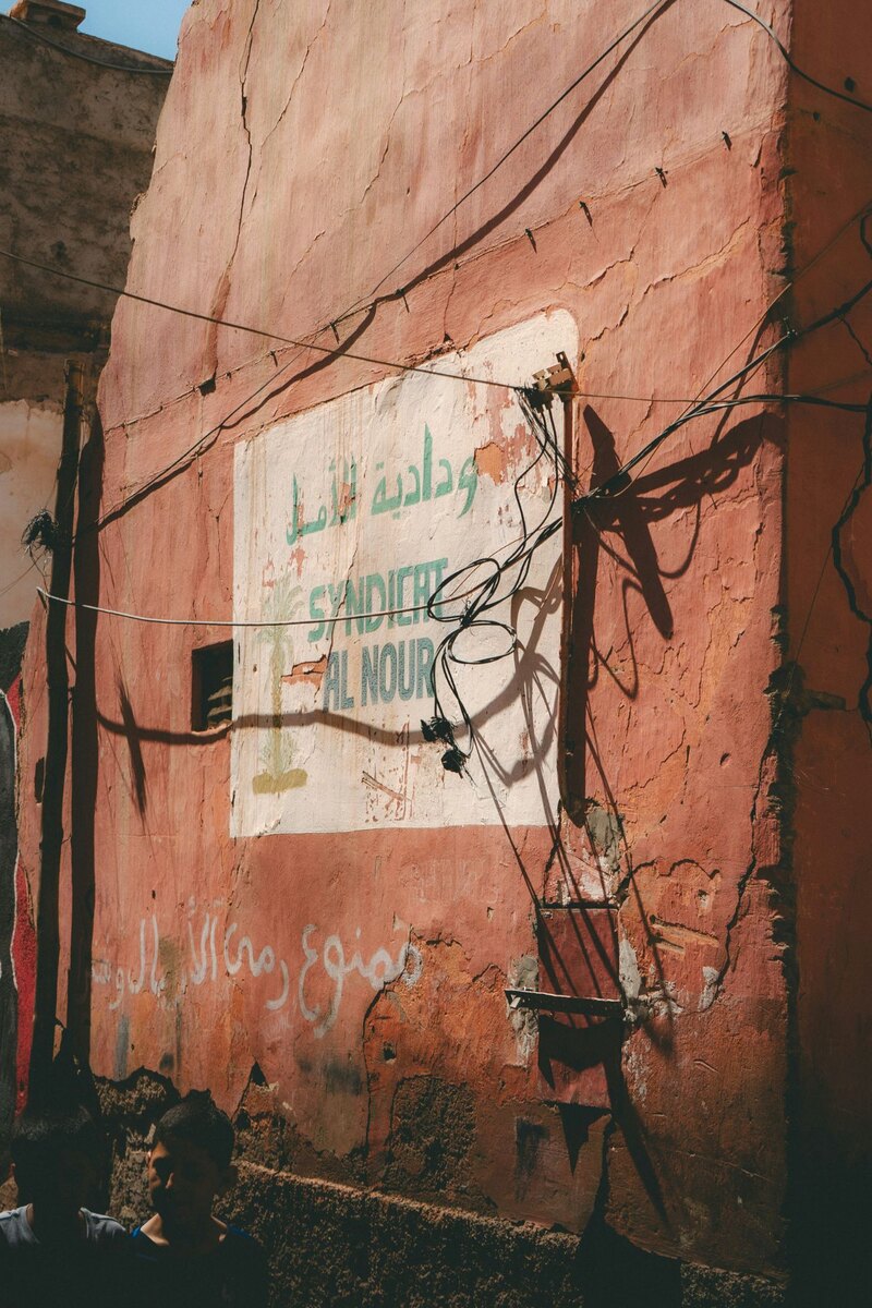 A faded painted sign on a cracked pink wall, After